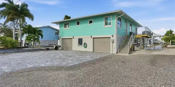 Image 2: Coastal inspired home with decorative driveway, stairway, and an attached garage - Virtually Edited Image