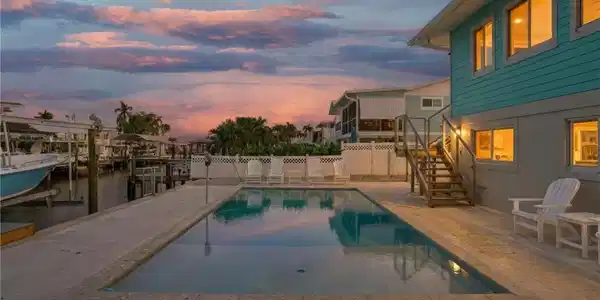 Image 4: Pool at dusk with a patio, stairway, boat lift, a boat dock, and a water view - Virtually Edited Image