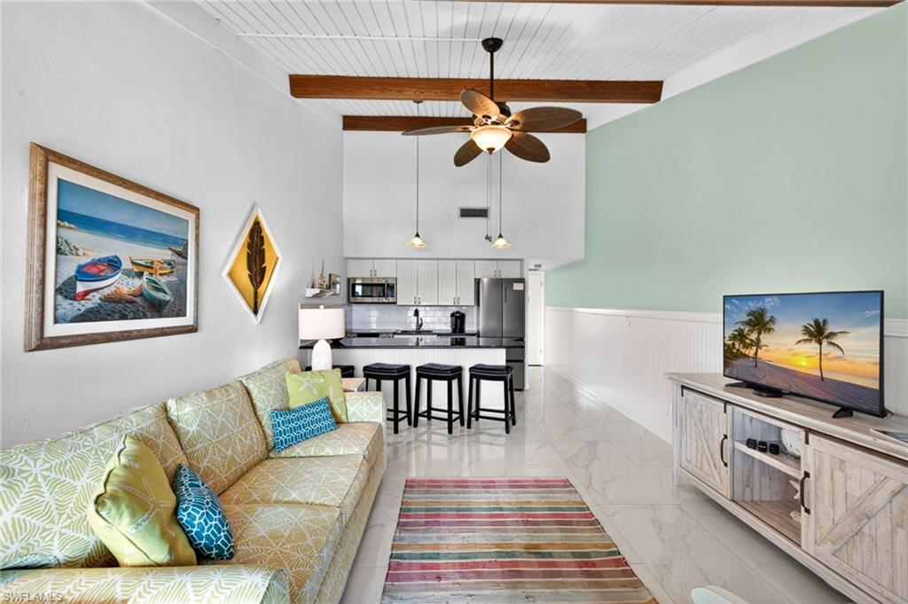 Image 3: Open-concept living area with high vaulted ceilings, exposed wood beams, and a white plank ceiling