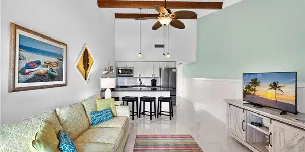 Image 3: Open-concept living area with high vaulted ceilings, exposed wood beams, and a white plank ceiling