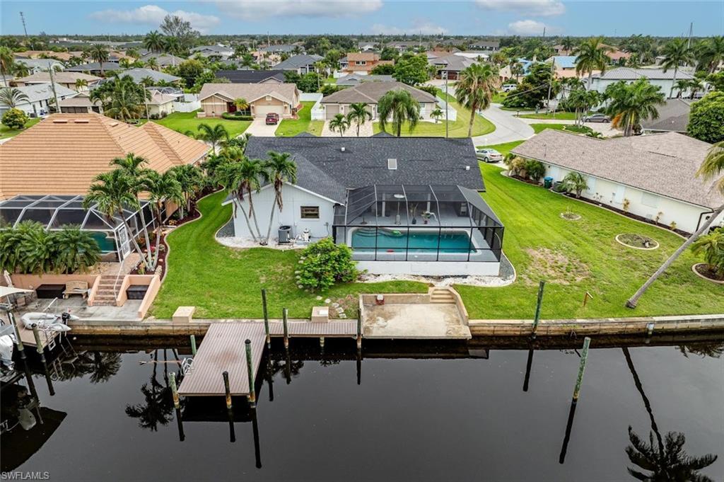 Image 2: Aerial perspective of suburban area featuring a pool and a nearby body of water