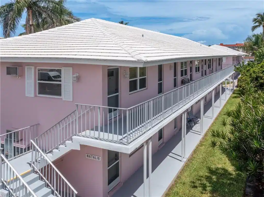 Image 1: Two-story residential building featuring a tile roof, light pink exterior, and white window shutters