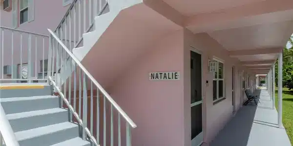 Image 3: Exterior building featuring a pastel pink facade and covered walkways