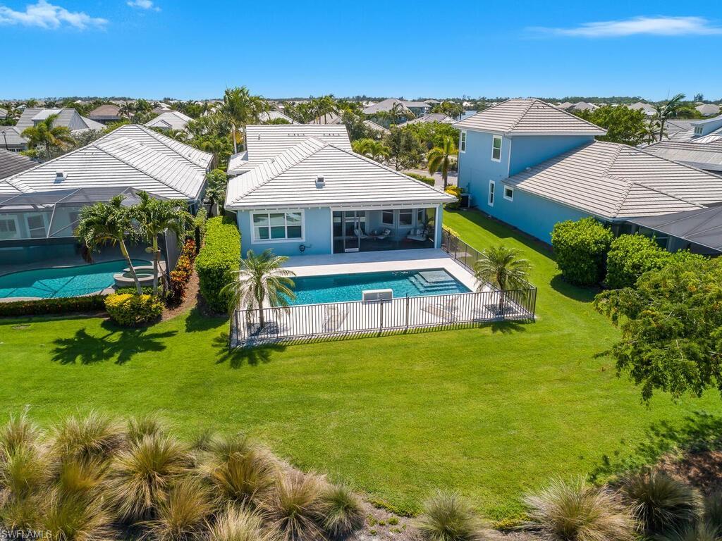 Image 2: Rear view of property featuring a residential view, an outdoor pool, and lots of green space.