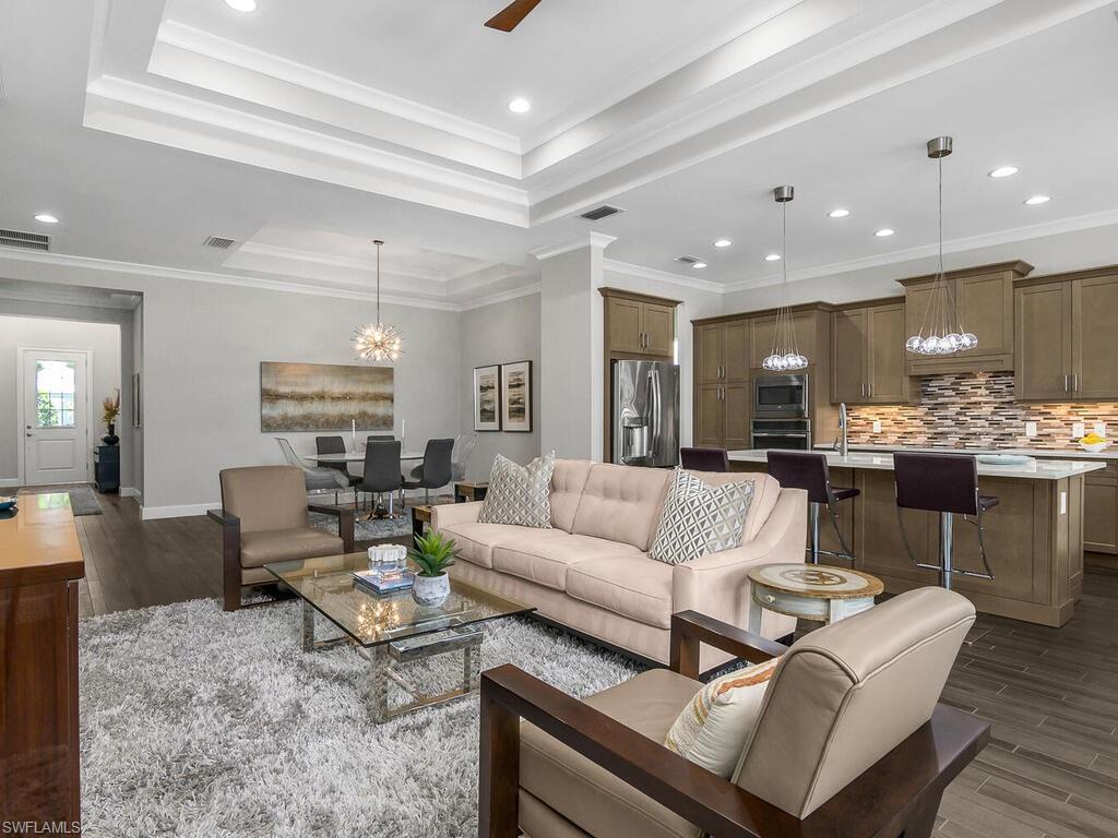Image 3: Living room with plank tile flooring, a raised ceiling, a chandelier, recessed lighting, and baseboards
