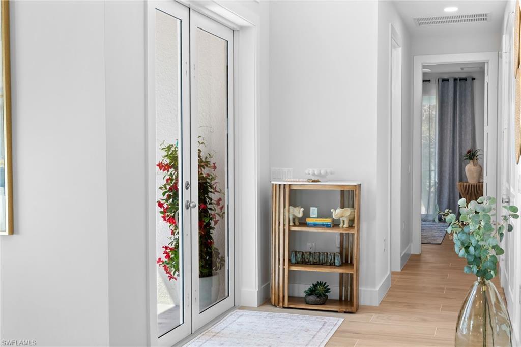 Image 4: Entryway with French doors featuring textured glass, leading to an outdoor area with vibrant red foliage