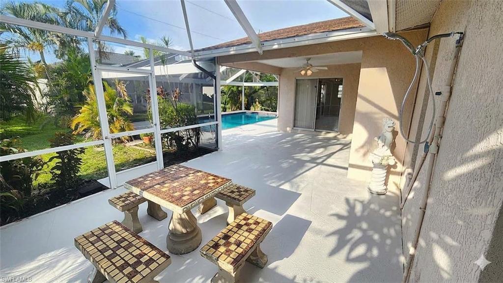 Image 4: Screened outdoor patio featuring a swimming pool, covered porch, and mature tropical landscaping