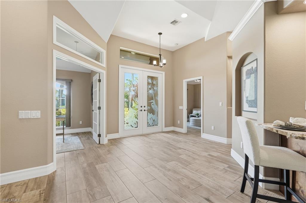 Image 3: Entryway featuring Wide wood-finish plank tile flooring, double French doors with decorative etched glass, and transom windows
