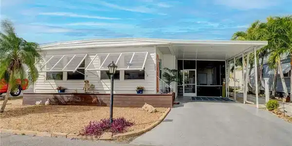 Image 3: Manufactured / mobile home with an attached carport, a sunroom, and driveway