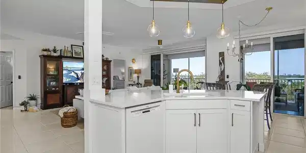Image 3: Kitchen featuring white dishwasher, white cabinetry, open floor plan, a chandelier, and light tile patterned flooring