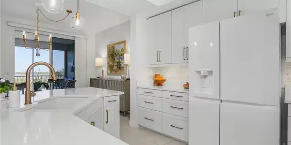 Image 4: Kitchen with white refrigerator with ice dispenser, white cabinets, decorative light fixtures, backsplash, and light tile patterned floors