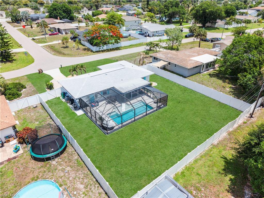 Image 3: Fenced property featuring a screened-in pool, expansive manicured lawn, and a light-colored roof