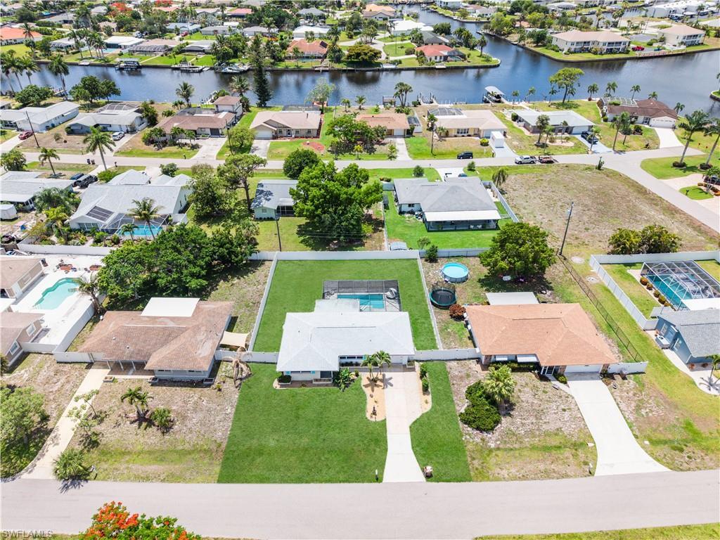Image 4: Aerial perspective showcasing a residential lot with a paved driveway, front lawn, and mature palm trees
