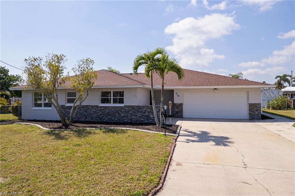 Image 2: Single story home featuring driveway, stone siding, stucco siding, an attached garage, and a front yard