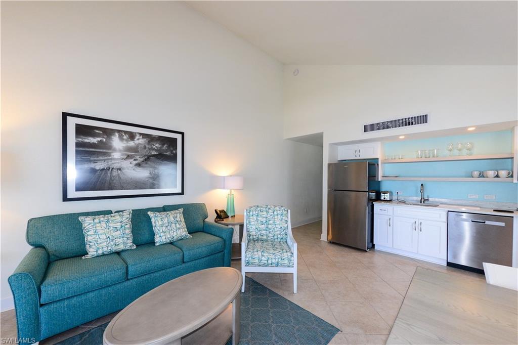 Image 2: Living room with high vaulted ceiling, bar with sink, and light tile patterned floors