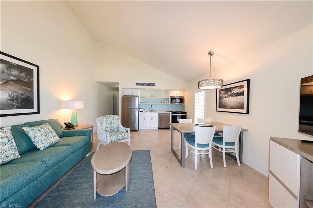Image 3: Living area with light tile patterned floors, high vaulted ceiling, bar with sink, and baseboards