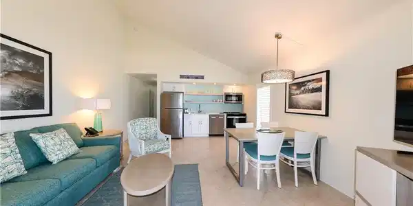 Image 3: Living area with light tile patterned floors, high vaulted ceiling, bar with sink, and baseboards