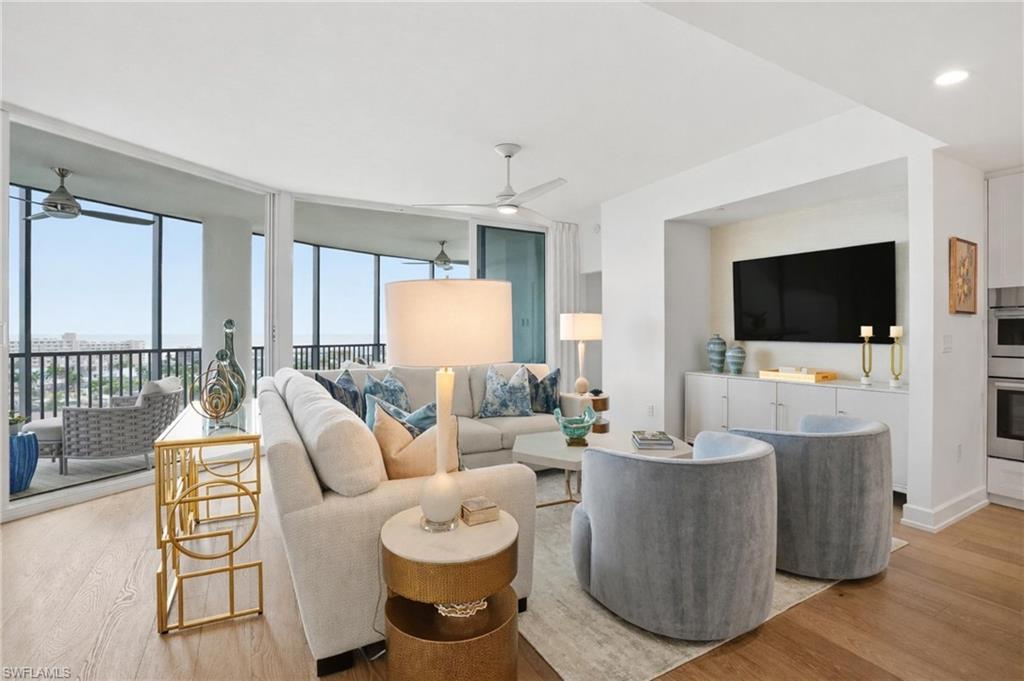 Image 2: Living room featuring floor to ceiling windows and light wood-style flooring - Virtually Edited Image
