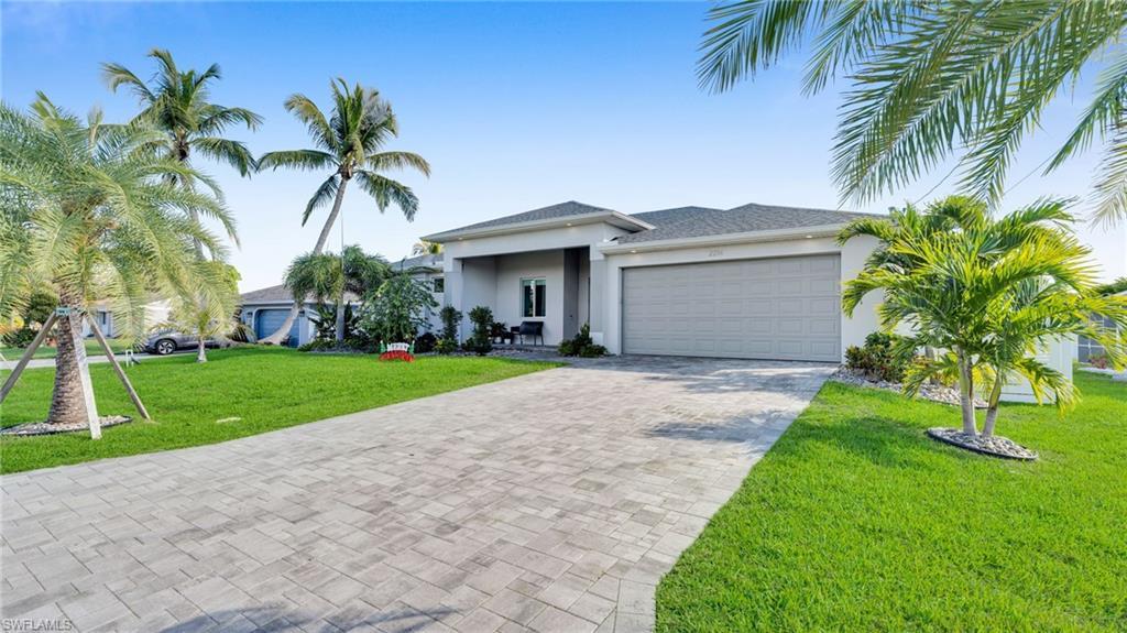 Image 2: View of front of home featuring a front yard, stucco siding, decorative driveway, and an attached garage