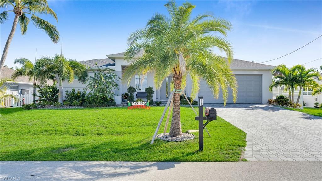 Image 3: View of front of property with a front lawn, decorative driveway, stucco siding, and a garage