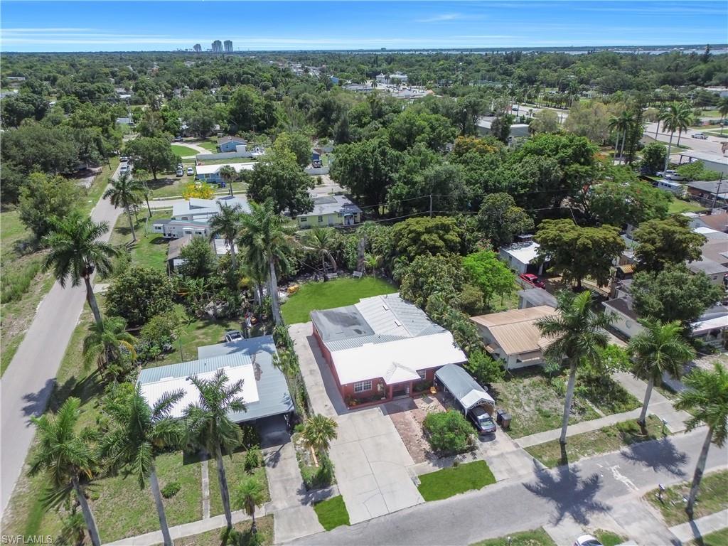 Image 2: Property featuring mature palm trees, a paved driveway, and a covered carport