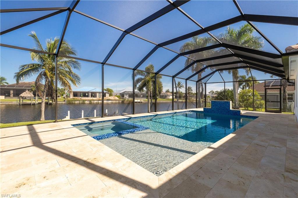 Image 3: View of swimming pool featuring a sunroom, a pool with connected hot tub, glass enclosure, a patio, and a water view