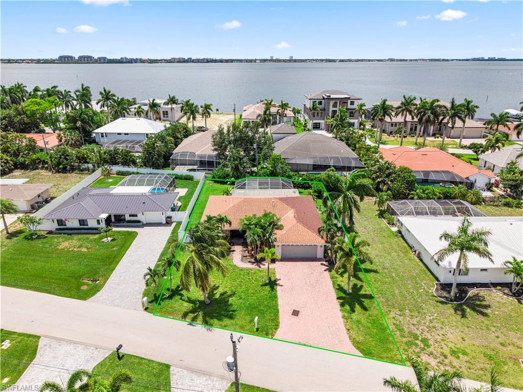Image 3: Aerial perspective showcasing a waterfront property with a red tile roof and a paver driveway