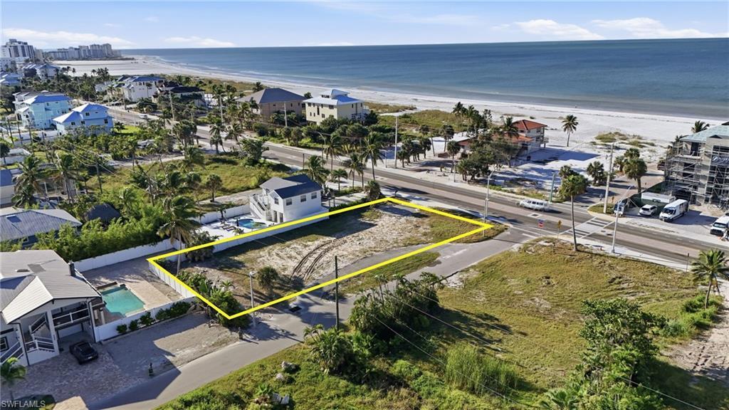 Image 4: Aerial overview of property's location featuring property parcel outlined and waterfront with a beach - Virtually Edited Image