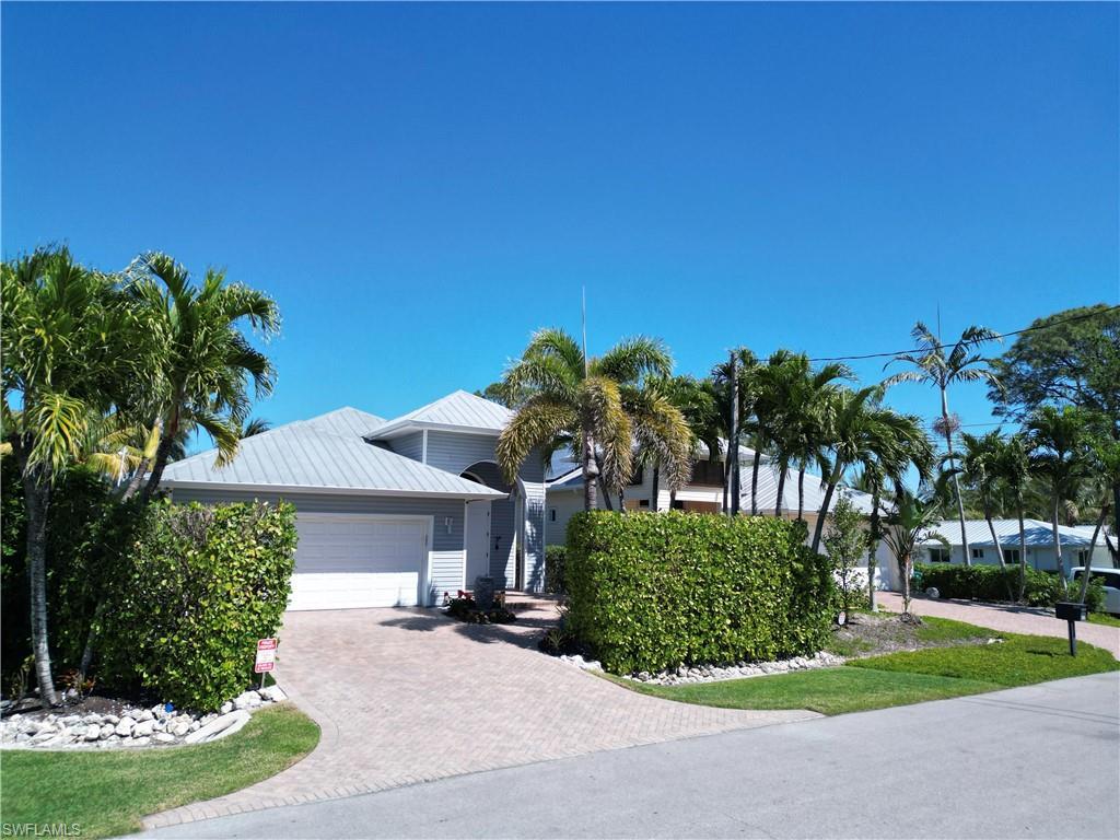 Image 4: Coastal-style residence featuring a light gray exterior, metal roof, and a two-car garage