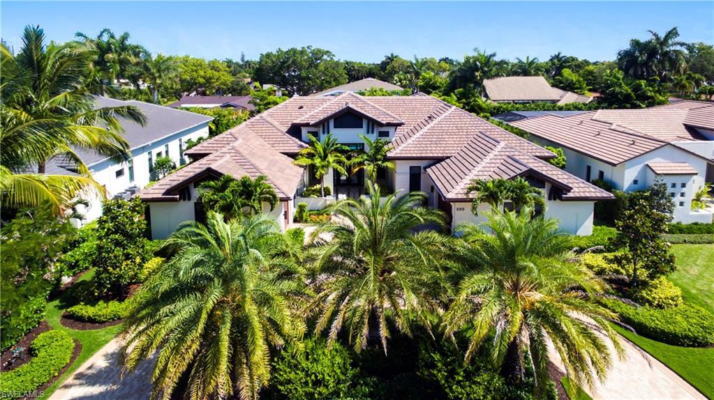Image 2: Expansive estate featuring a terracotta tile roof, stucco exterior, lush tropical landscaping with mature palm trees, and a paver driveway