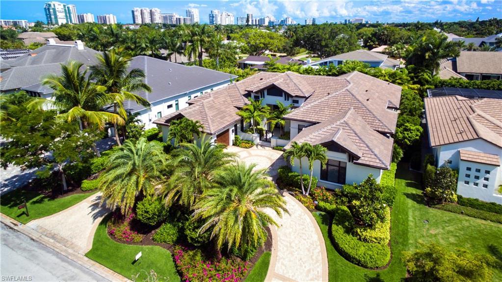 Image 3: Spacious property featuring a tiled roof, paver driveway, mature palm trees, manicured lawns, and lush landscaping