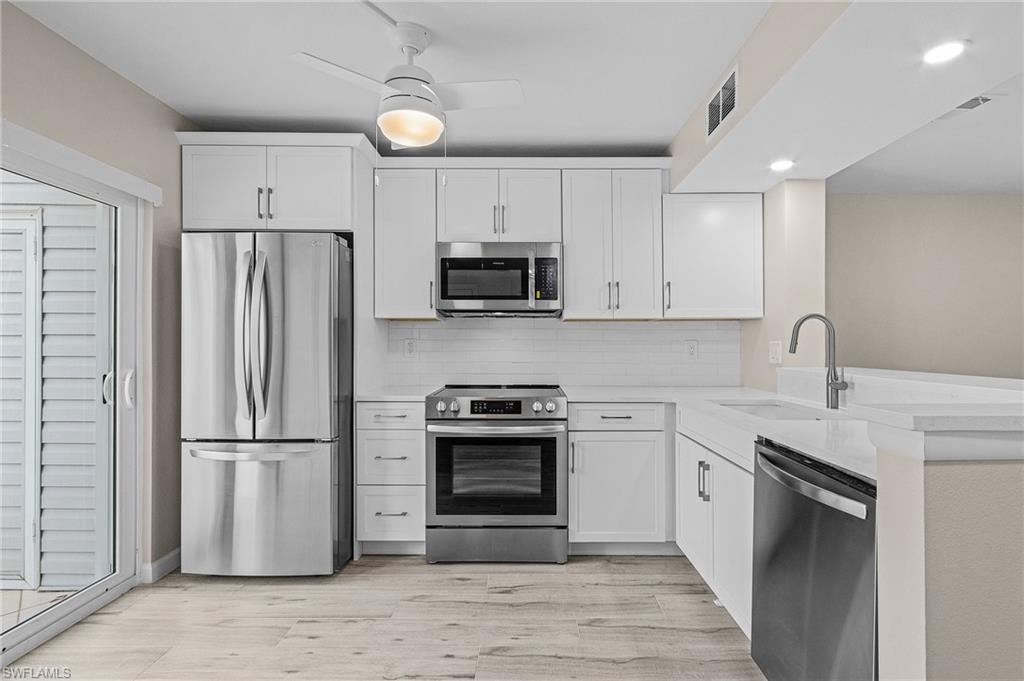 Image 4: Kitchen with sink, light hardwood / wood-style floors, ceiling fan, stainless steel appliances, and white cabinets