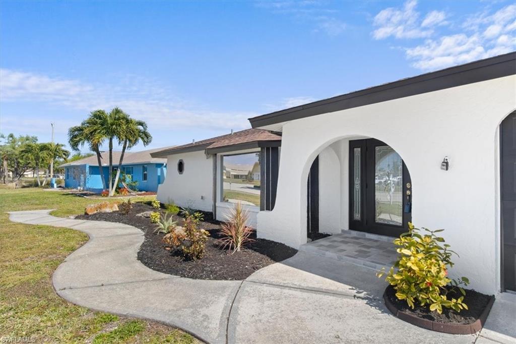 Image 3: Property entrance with stucco siding and a lawn