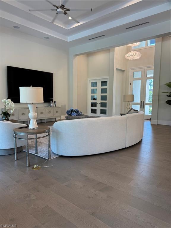 Image 3: Living area with a ceiling fan, wood finished floors, visible vents, baseboards, and french doors
