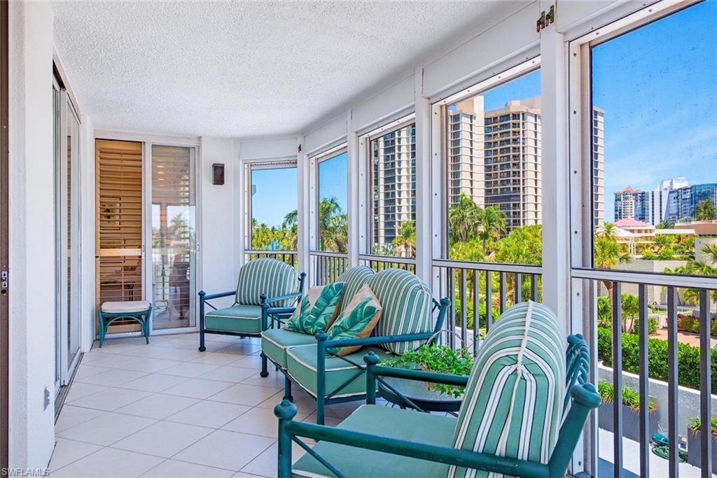 Image 2: Enclosed balcony featuring large windows, sliding glass doors, white tiled flooring, and a flat white ceiling