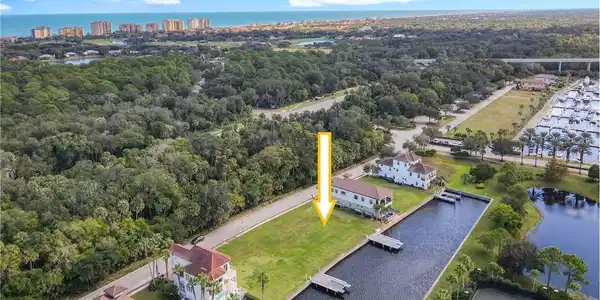 Image 3: Waterfront lot featuring a private boat dock, green lawn, established trees, and canal access