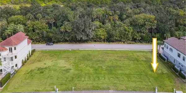 Image 4: Expansive waterfront lot featuring a green lawn, private dock, and concrete seawall