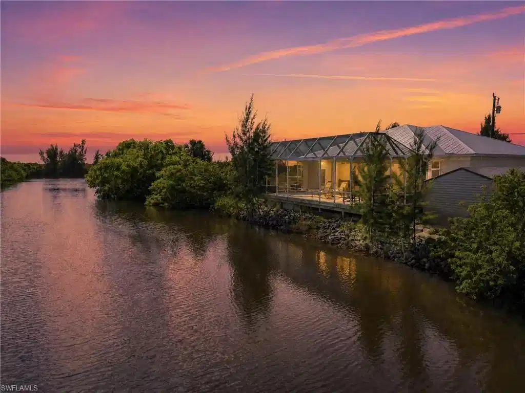 Image 1: Waterfront property with a large screened-in porch, expansive wood deck, and a metal roof