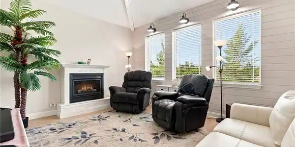 Image 3: Living space featuring a fireplace with a mantel, vaulted ceiling, and wood-finish flooring