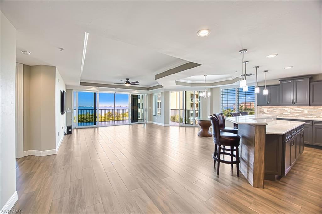 Image 4: Kitchen featuring a tray ceiling, a breakfast bar area, open floor plan, dark wood-type flooring, and light stone countertops