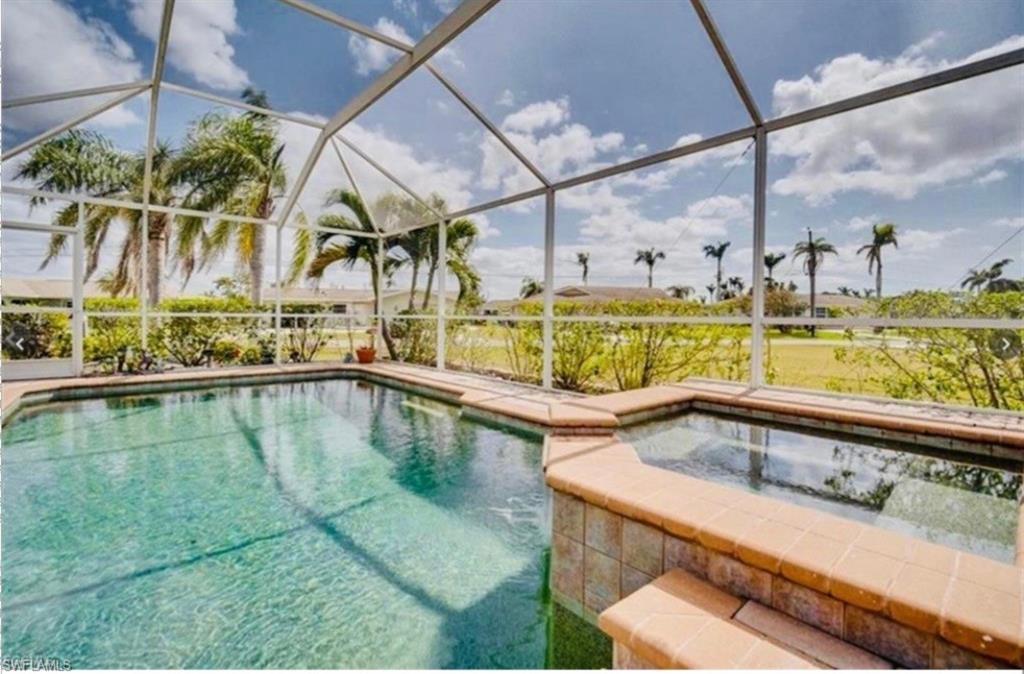 Image 1: View of pool with glass enclosure, a sunroom, a pool with connected hot tub, and a patio