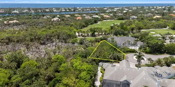Image 3: Aerial perspective of suburban area with a golf club, property parcel outlined, a tree filled landscape, and a large body of water