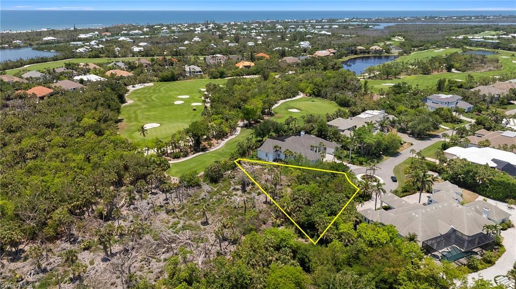Image 4: Aerial perspective of suburban area featuring a local golf course, a large body of water, property parcel outlined, and a tree filled landscape