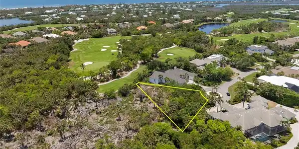 Image 4: Aerial perspective of suburban area featuring a local golf course, a large body of water, property parcel outlined, and a tree filled landscape