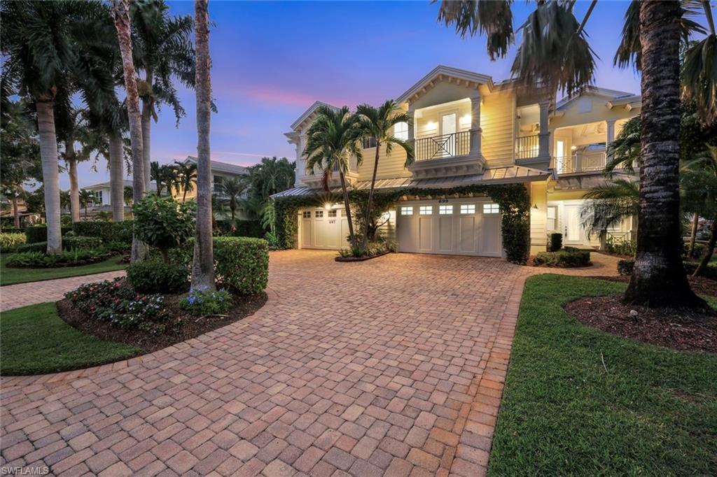 Image 3: Front view of the home at dusk featuring the paved driveway, second floor balcony and 2-car garage