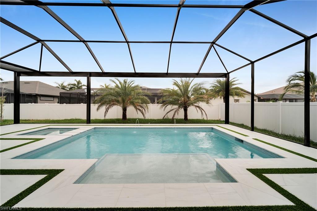 Image 2: Screened outdoor living area featuring a rectangular pool with an integrated spa, expansive white tile decking, and decorative artificial turf accents