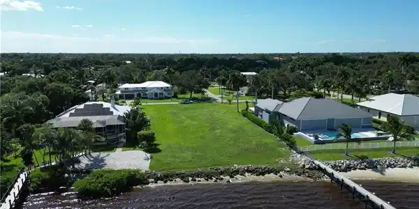 Image 2: Expansive waterfront property featuring a grassy lot, a long pier, and mature landscaping
