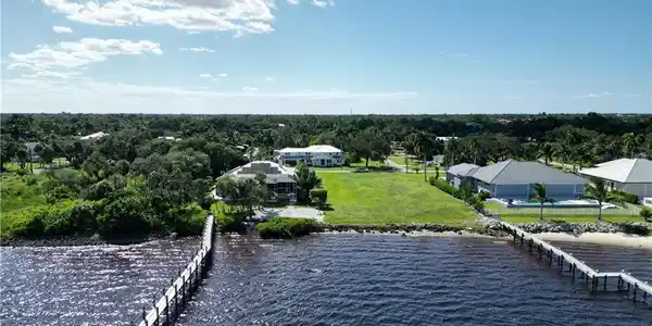 Image 3: Waterfront property featuring a private dock, sandy shoreline, and expansive grassy area