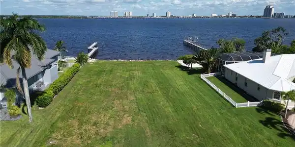 Image 4: Expansive waterfront lot featuring a manicured lawn, established landscaping, and direct water access with a private dock