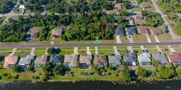 Image 3: Expansive undeveloped lot featuring mature trees and direct road frontage